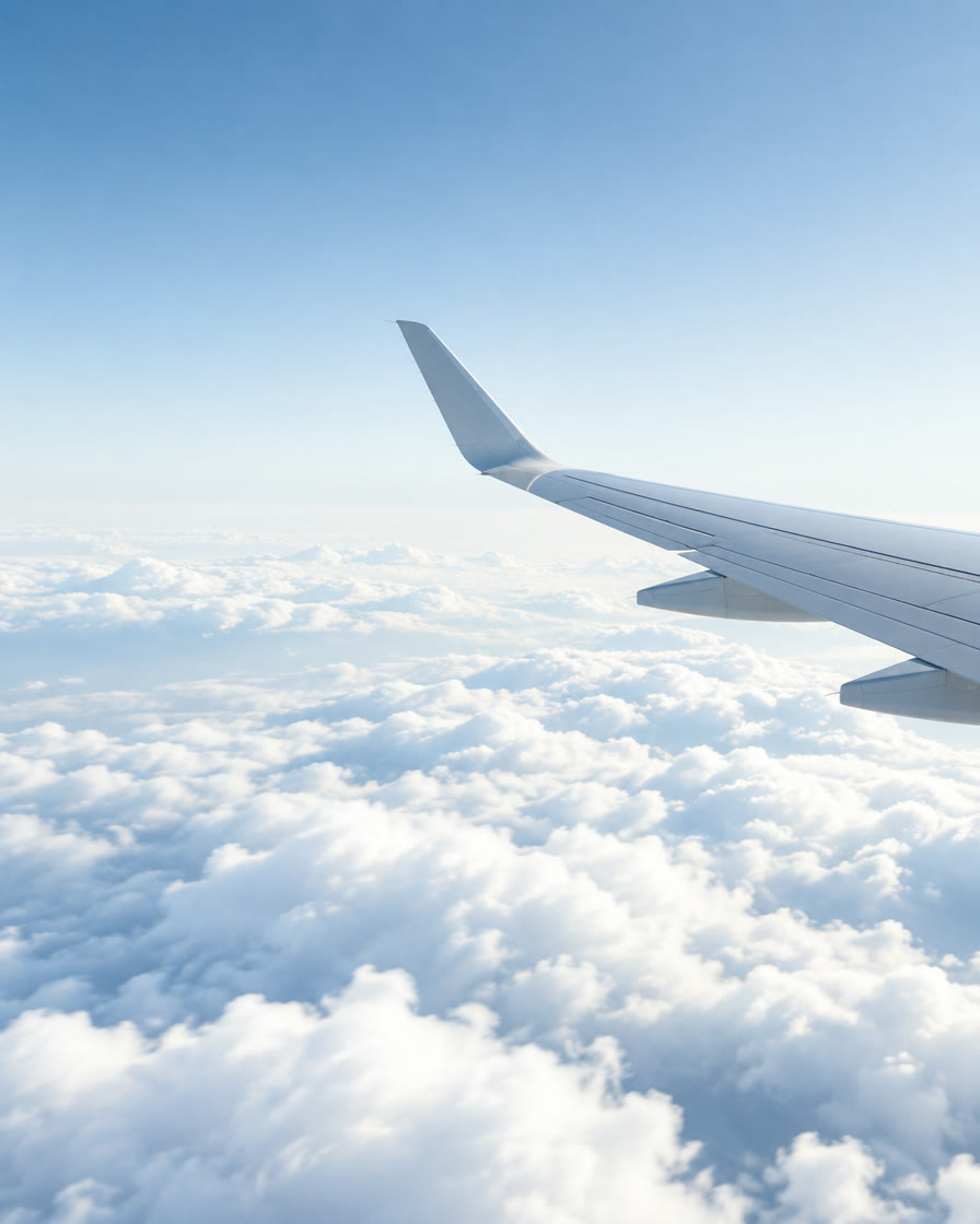 Airplane wing above a sea of clouds in bright daylight